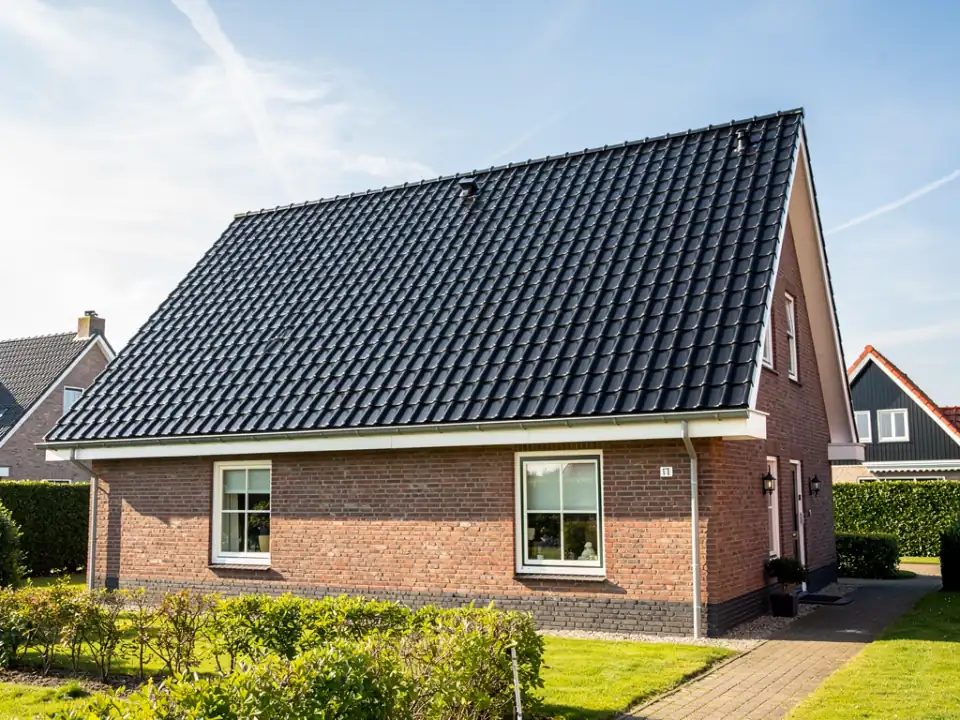 Vrijstaande bakstenen woning met een schoon, egaal donker pannendak