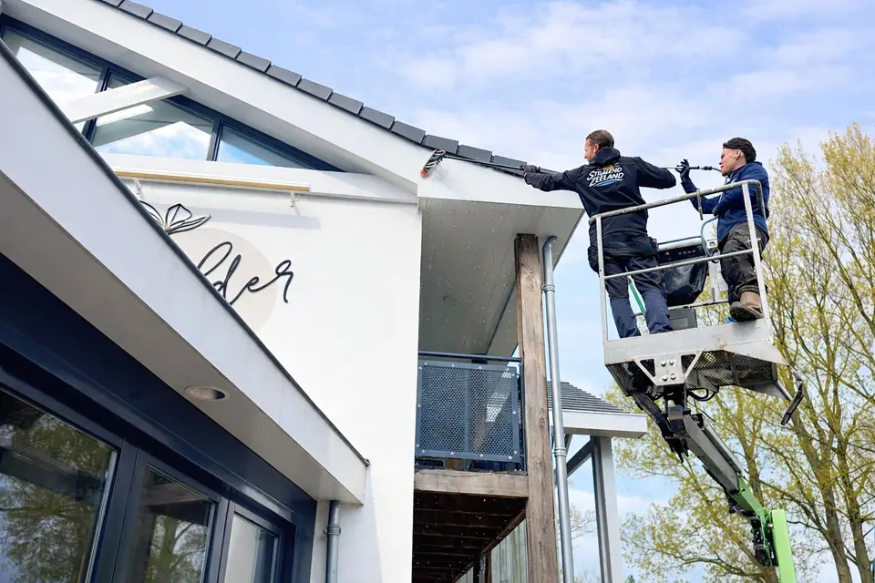 Twee glazenwassers van Stralend Zeeland op een hoogwerker bij een hotel
