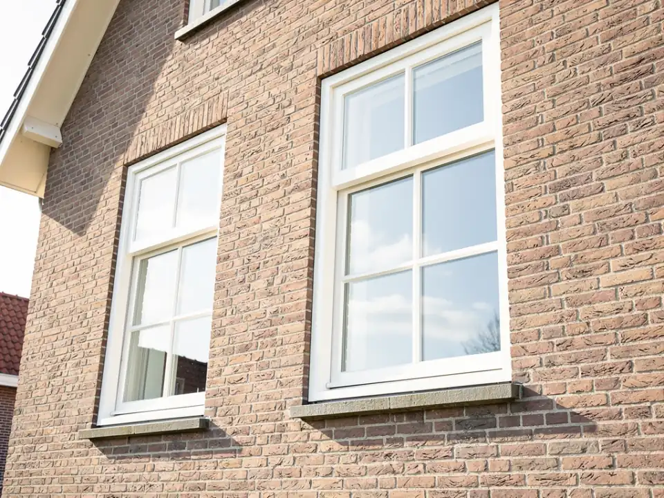 Streeploos schone ramen met witte kozijnen die de blauwe lucht weerspiegelen