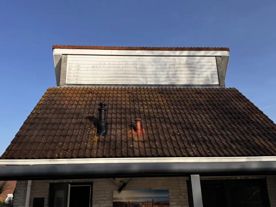 Donker bemost pannendak onder een witte dakopbouw