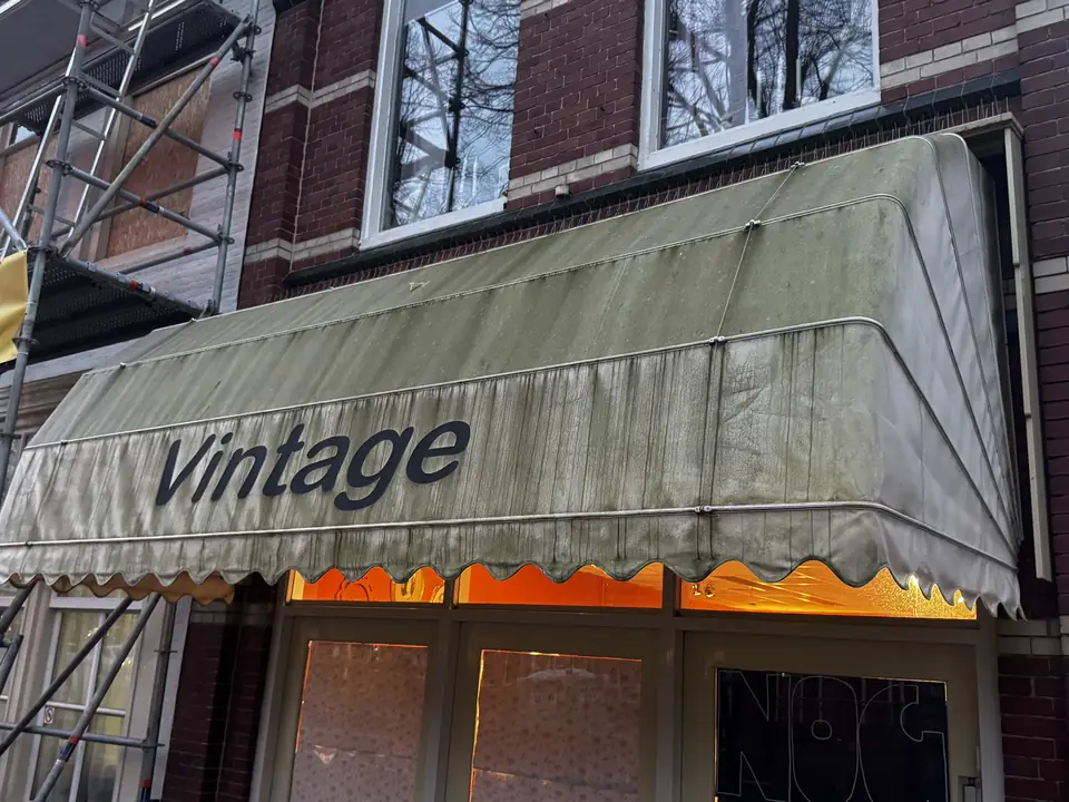 Luifel boven een winkel, grauw en groen van de aanslag